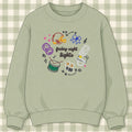 Sage green crewneck sweatshirt with embroidered football helmet, cheer bow, drum and marching band hat around friday night lights script lettering