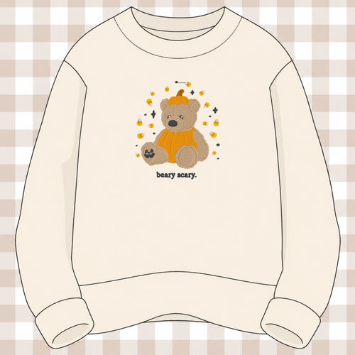 Cream crewneck sweatshirt with an embroidered teddy bear wearing a pumpkin costume surrounded by candy corn, reading beary scary